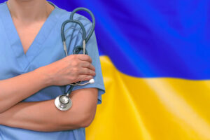 Female nurse or doctor with stethoscope in hand on the background of the Ukraine flag. Surgery concept in Ukraine